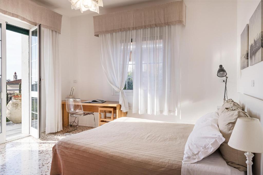 a white bedroom with a bed and a window at Casa delle Zagare in San Bartolomeo al Mare