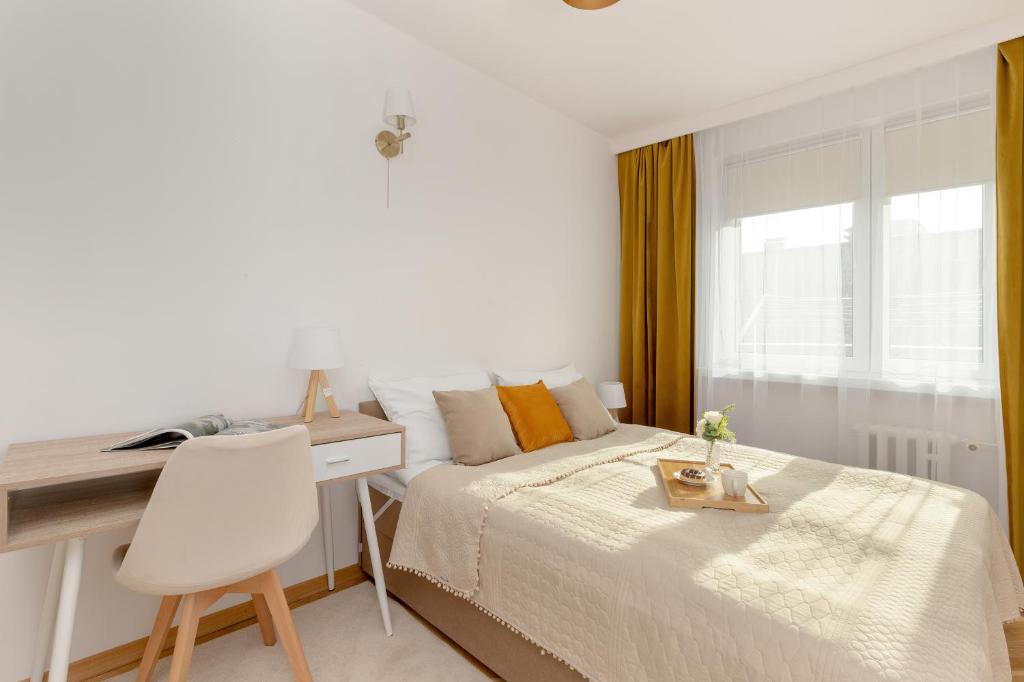 a bedroom with a bed and a desk and a window at Jagiellońska Apartments Przymorze Beach by Renters in Gdańsk