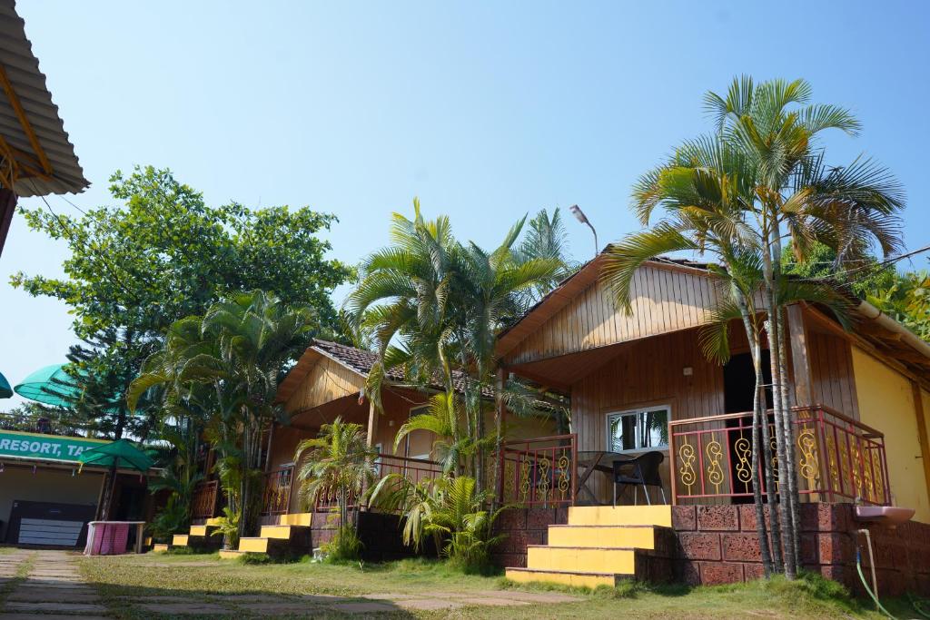 a house with palm trees in front of it at Nisarga Lake Resort in Satara