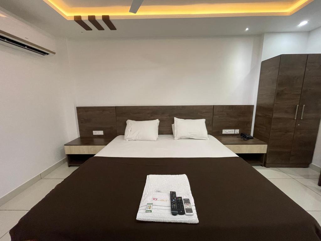 a bedroom with a bed with two remote controls on it at RK Residency in Kozhikode