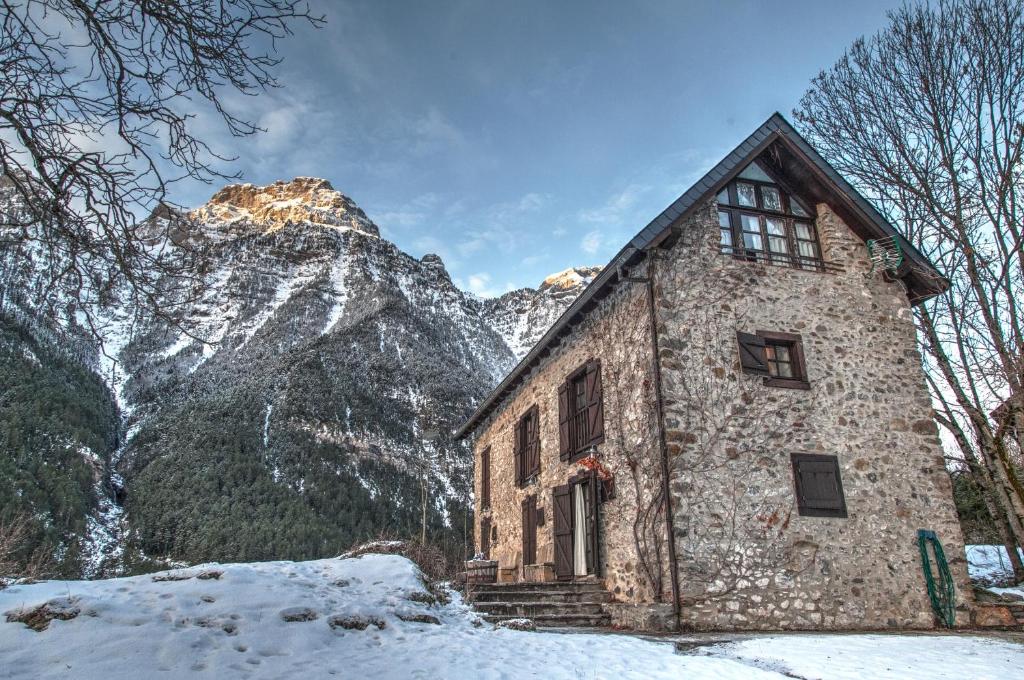 een stenen gebouw voor een met sneeuw bedekte berg bij Casas de Zapatierno in Espierba