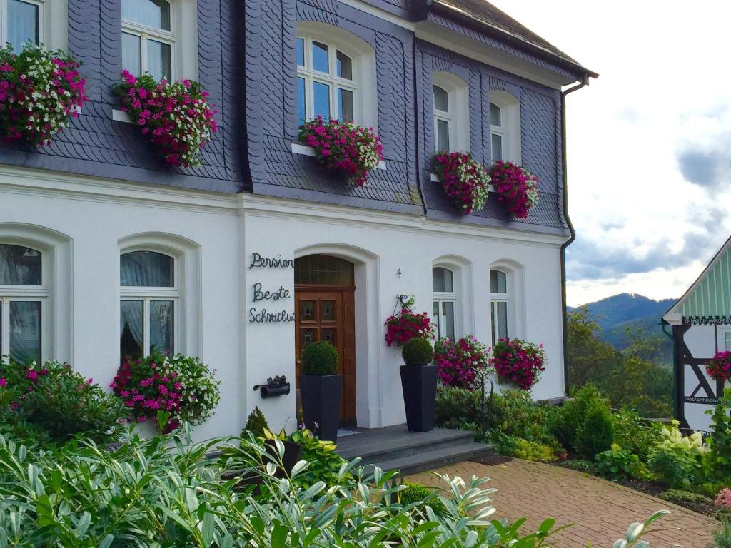 a white house with flower pots on the front of it at Pension Beste-Schnurbus in Schmallenberg