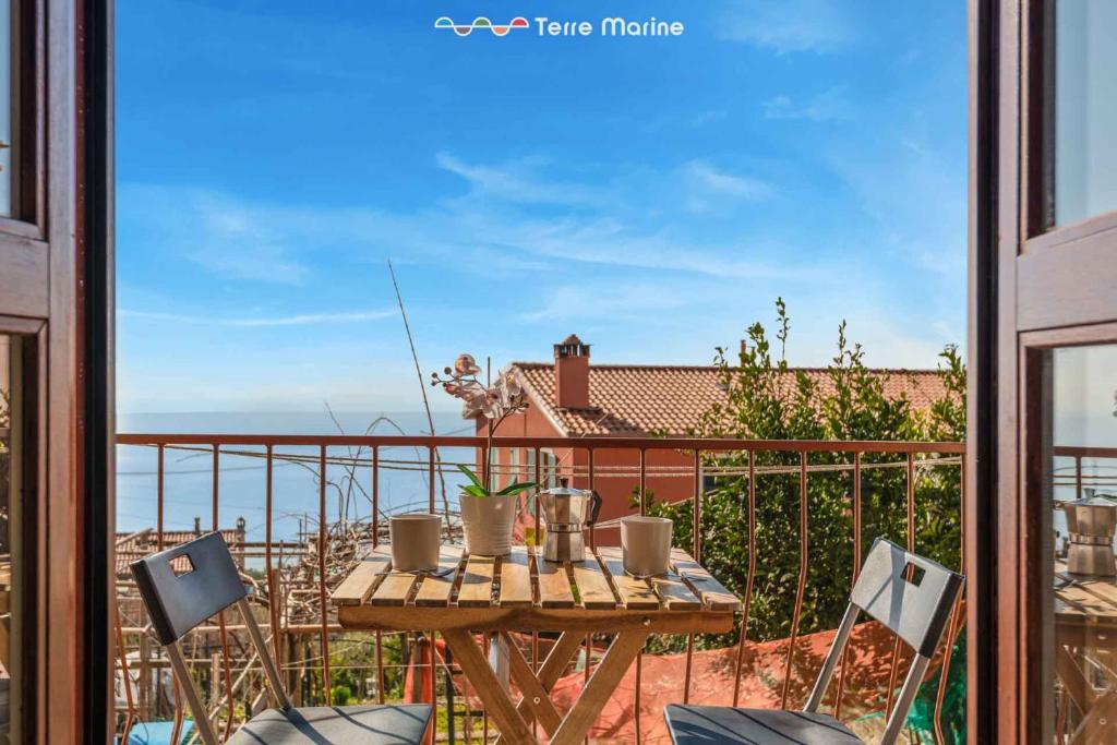 a table on a balcony with a view of the ocean at Il Nido delle Cinque Terre in Volastra