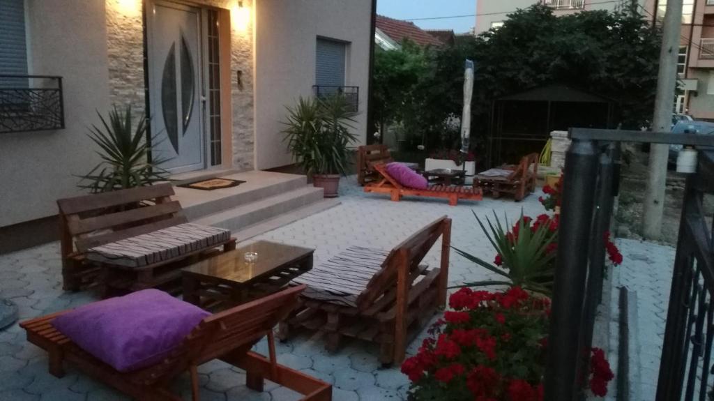eine Terrasse mit Bänken und einem Tisch mit lila Kissen in der Unterkunft Sreckovic Apartmani 2 in Kragujevac