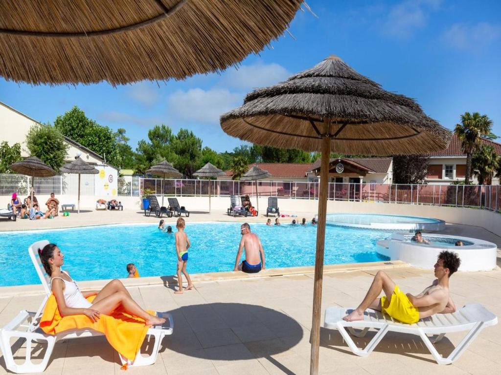 a group of people sitting in lawn chairs next to a pool at Camping Le Both d'Orouet in Saint-Jean-de-Monts