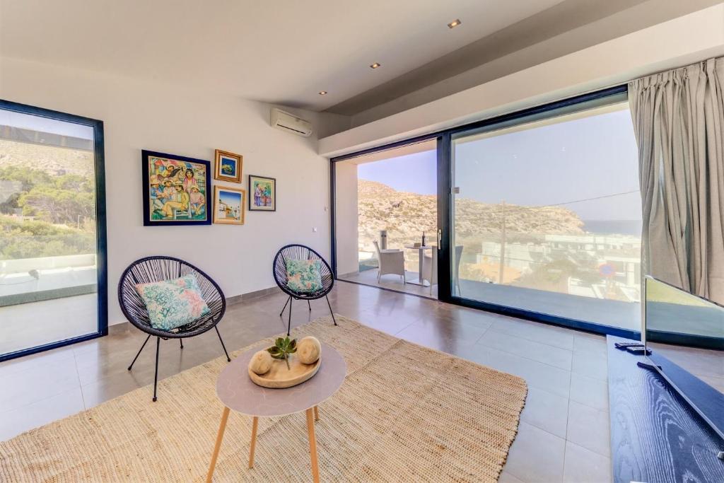 a living room with two chairs and a table at Cala Clara Beach Apartment by Sealand Villas in Cala de Sant Vicenc