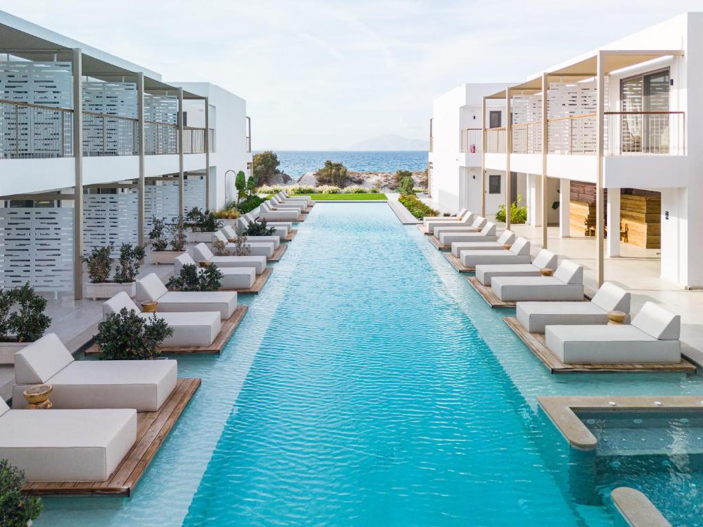 un'immagine di un hotel con piscina e sedie a sdraio di Paralos Kyma Dunes Adults Only a Mastichárion