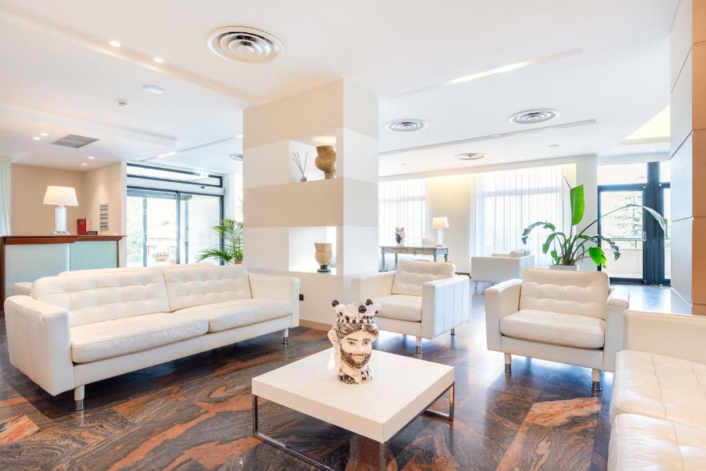 a living room with white couches and a table at Hotel Pomara in San Michele di Ganzaria