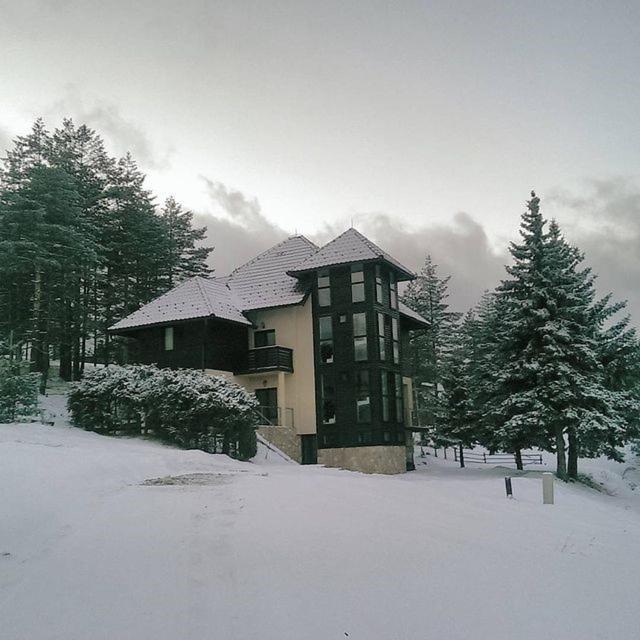 a large building with snow on it in a yard at Vila Zabac - Ski Center Tornik in Zlatibor