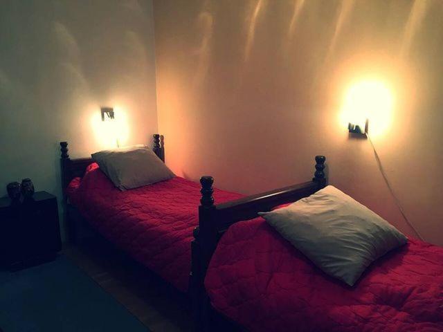 茲拉蒂博爾的住宿－Vila Zabac - Ski Center Tornik，一间卧室配有两张带红色床单和两张灯的卧室