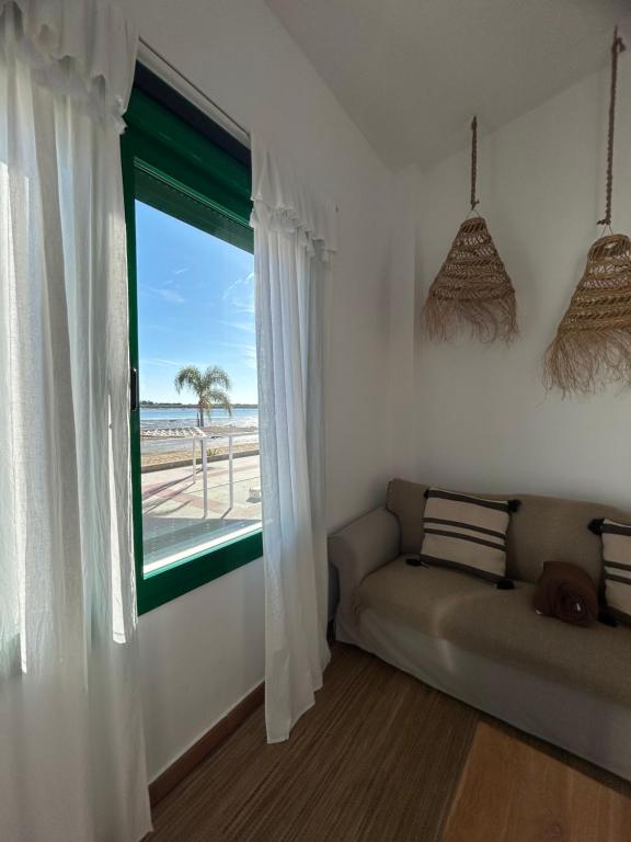 Habitación con sofá y ventana con vistas a la playa. en Apartamento en primera línea de playa, en El Rompido