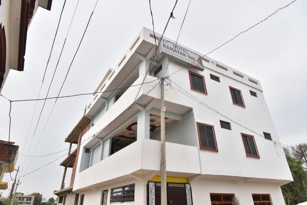 Un bâtiment blanc avec un panneau. dans l'établissement Hotel Ramayan Inn Free Pickup From Ayodhya Dham Junction, à Ayodhya