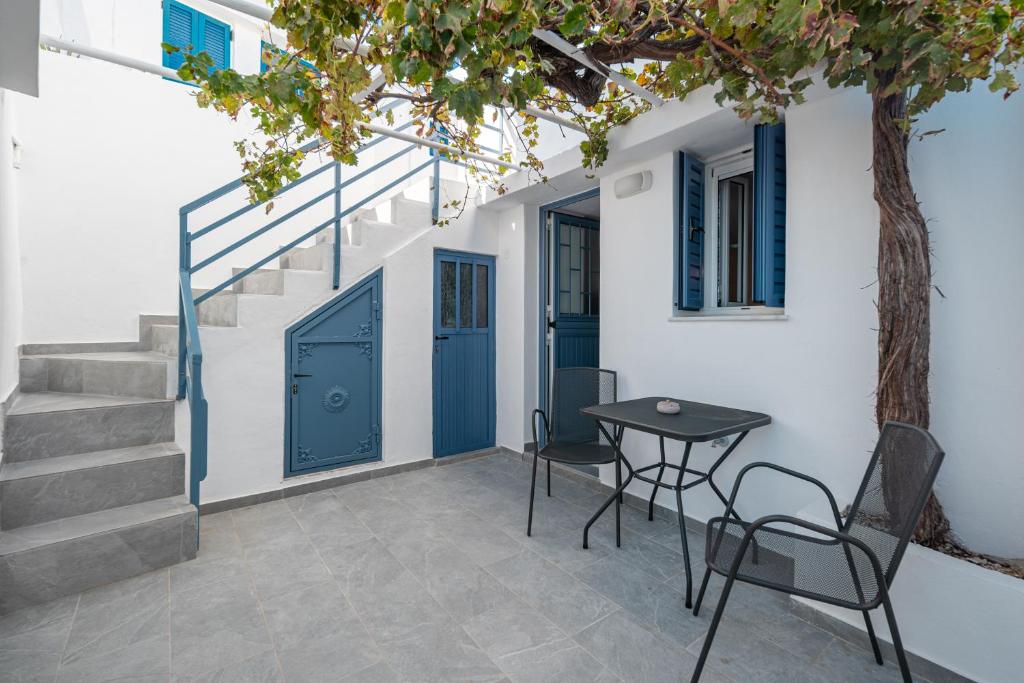 une table et des chaises à côté d'un bâtiment avec portes bleues dans l'établissement Michalis Home, à Sérifos Chora