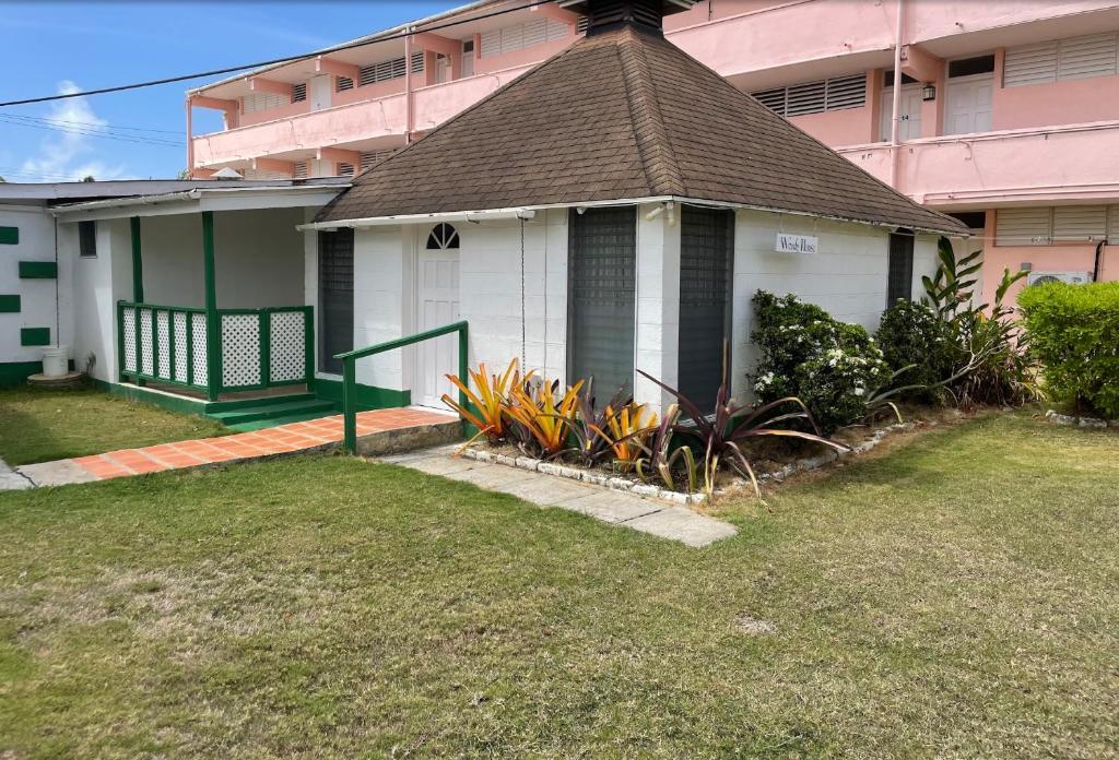 a small white house with a brown roof at The Monteray Hotel in Christ Church