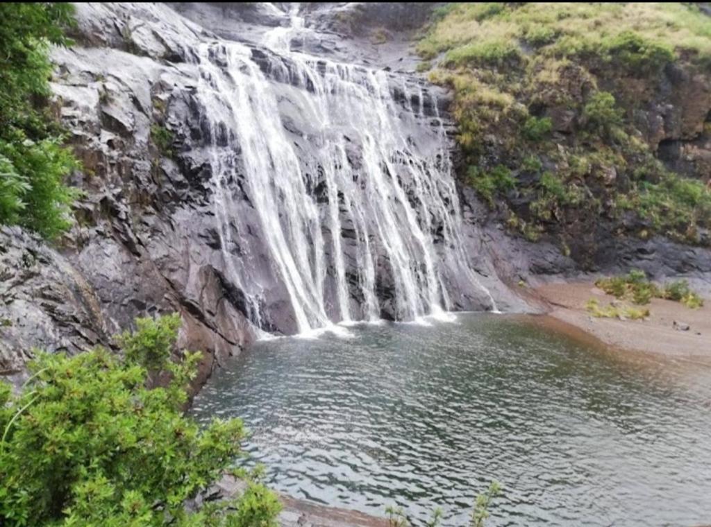 a waterfall over a body of water next to a beach at Morning Star Lodge. in Lirahalibonoe