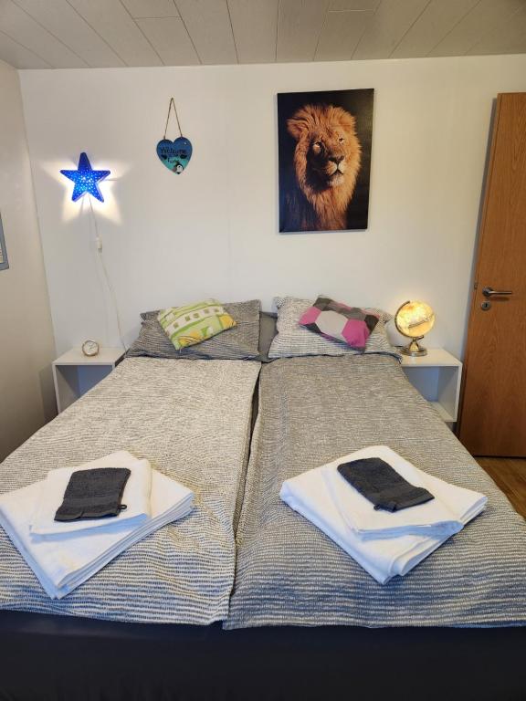 a bed with two towels and a lion on the wall at Pokój z prywatną łazienką i kuchnią z hot pot in Keflavík