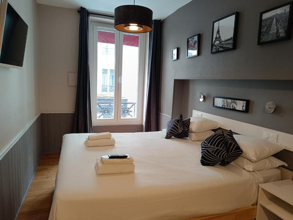 um quarto com uma grande cama branca e uma janela em Hôtel Apollo Opéra em Paris