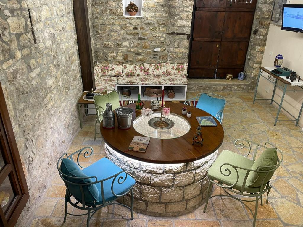 een tafel en stoelen in een kamer met een stenen muur bij The Well House - UNESCO in Berat