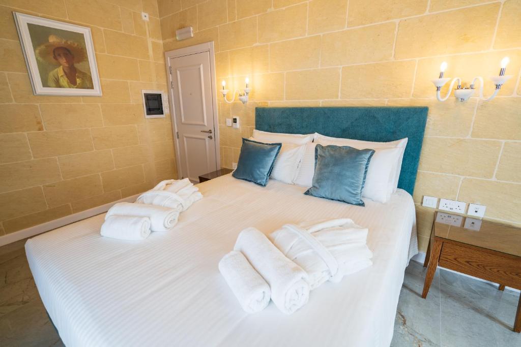 a bedroom with a white bed with towels on it at L-Eremita Boutique Hotel in Qala