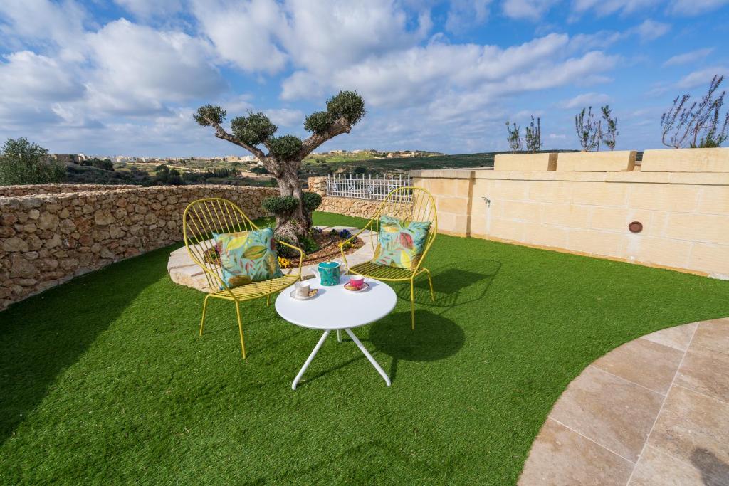 a patio with two chairs and a table on grass at L-Eremita Boutique Hotel in Qala