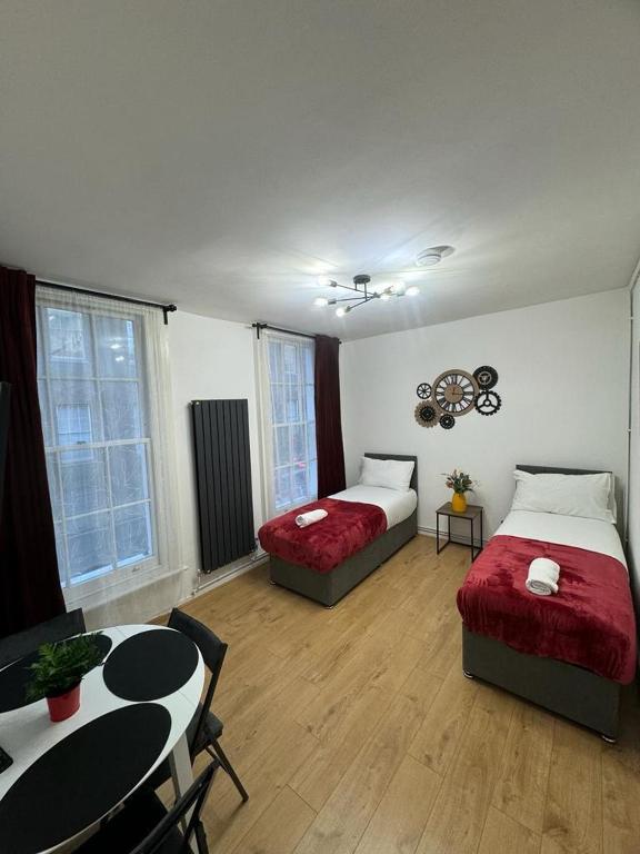 a room with two beds and a table and a dining room at Kings Cross-Euston Apartment in London