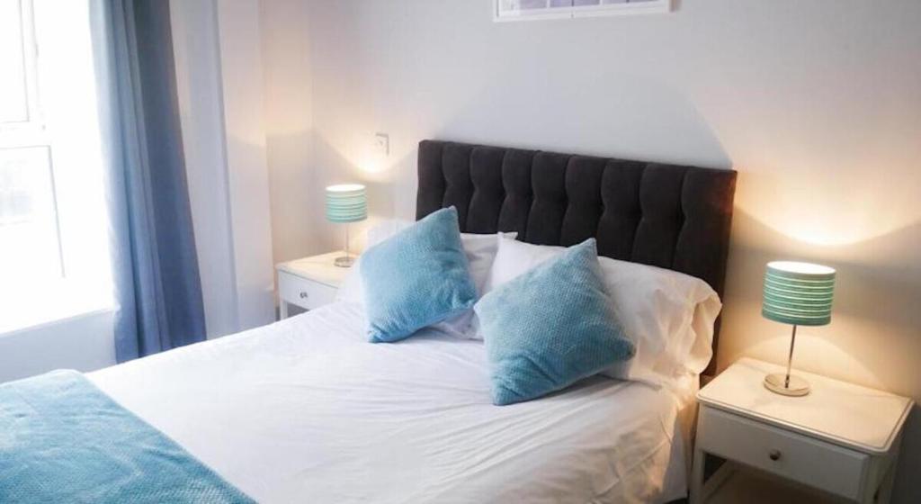 a bedroom with a bed with blue pillows on it at Wood Green Budget Rooms - Next to Mall & Metro Station - 10 Min to City Center in London