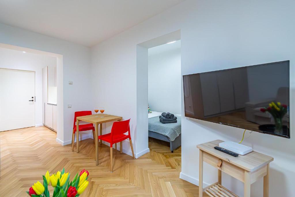 - un salon avec une table, des chaises rouges et une télévision dans l'établissement Near Žalgiris Arena Apartment, à Kaunas