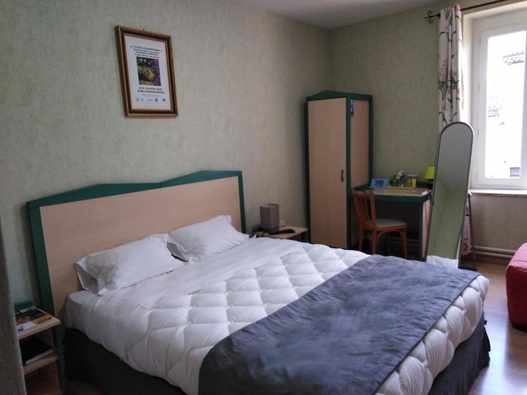 um quarto com uma cama grande e uma secretária com uma cadeira em Logis Hotel Des Voyageurs em Livron-sur-Drôme