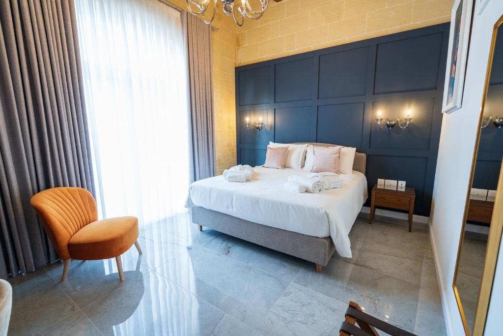 a bedroom with a large white bed and a chair at L-Eremita Boutique Hotel in Qala