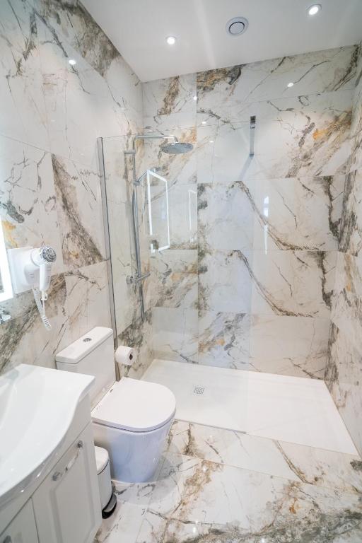 a white bathroom with a toilet and a shower at L-Eremita Boutique Hotel in Qala