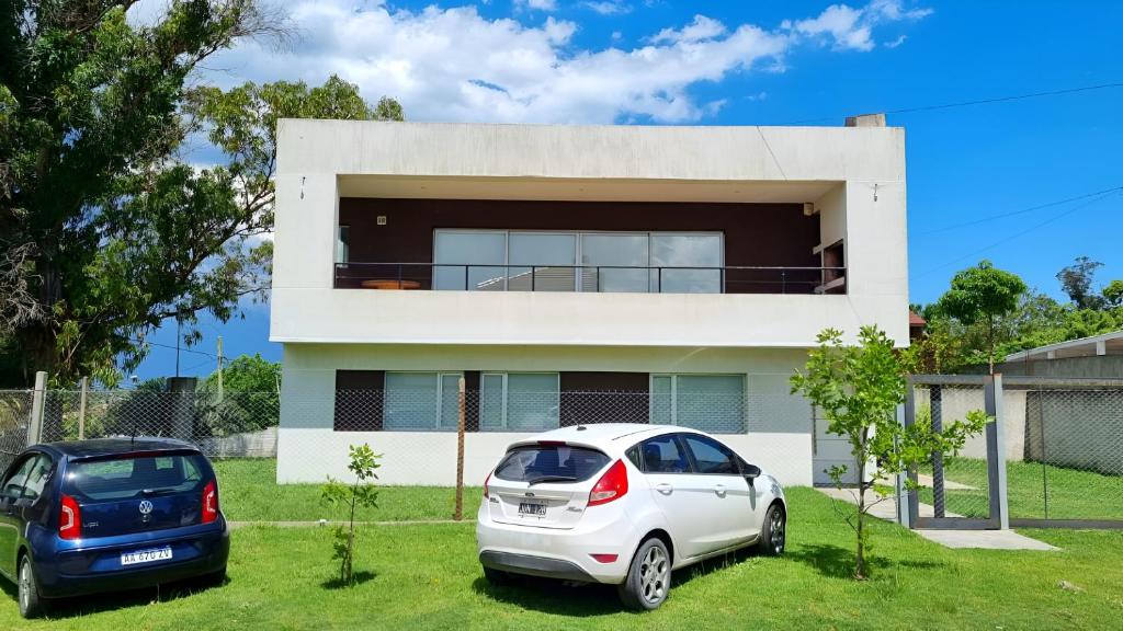 two cars parked in front of a white house at Casa sobre la Colina in Mar del Plata