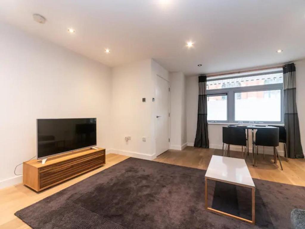 a living room with a flat screen tv and a table at Pass the Keys Spacious flat in Shoreditch in London