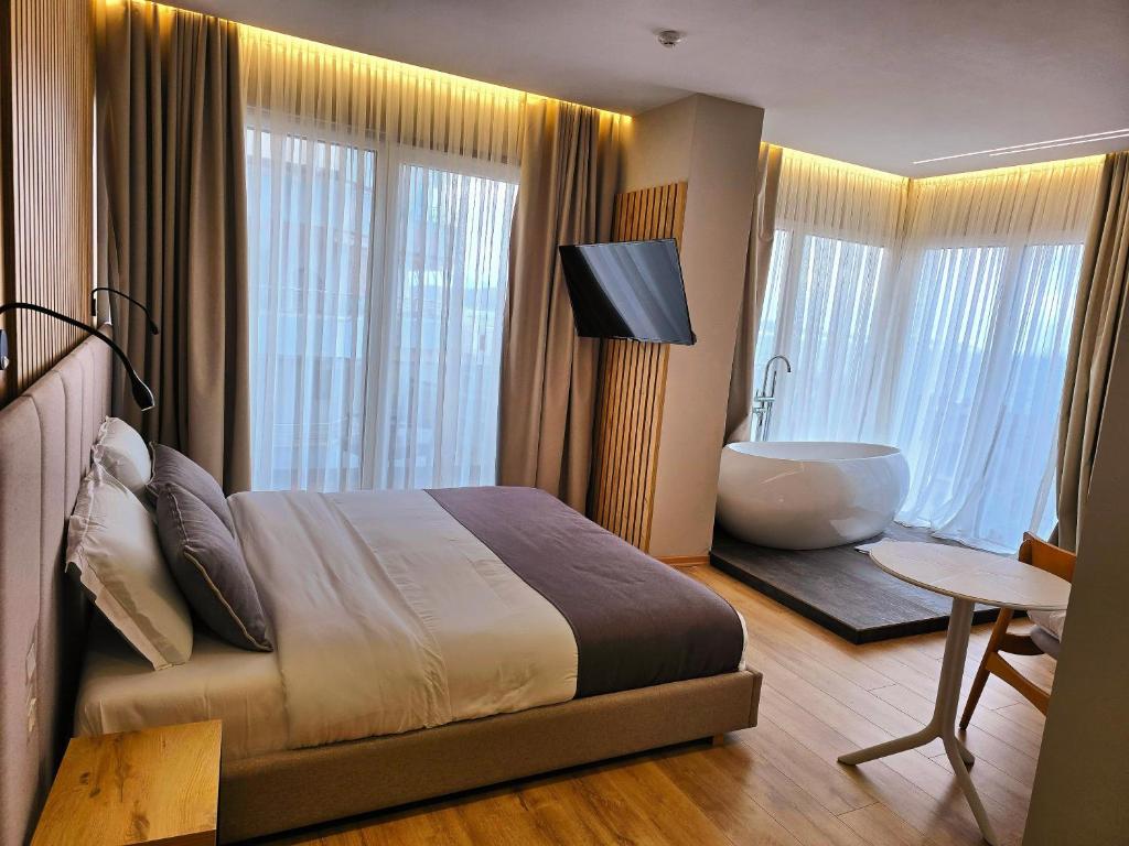 1 dormitorio con 1 cama grande y bañera junto a una ventana en Hotel Apollon Sarande, en Sarandë