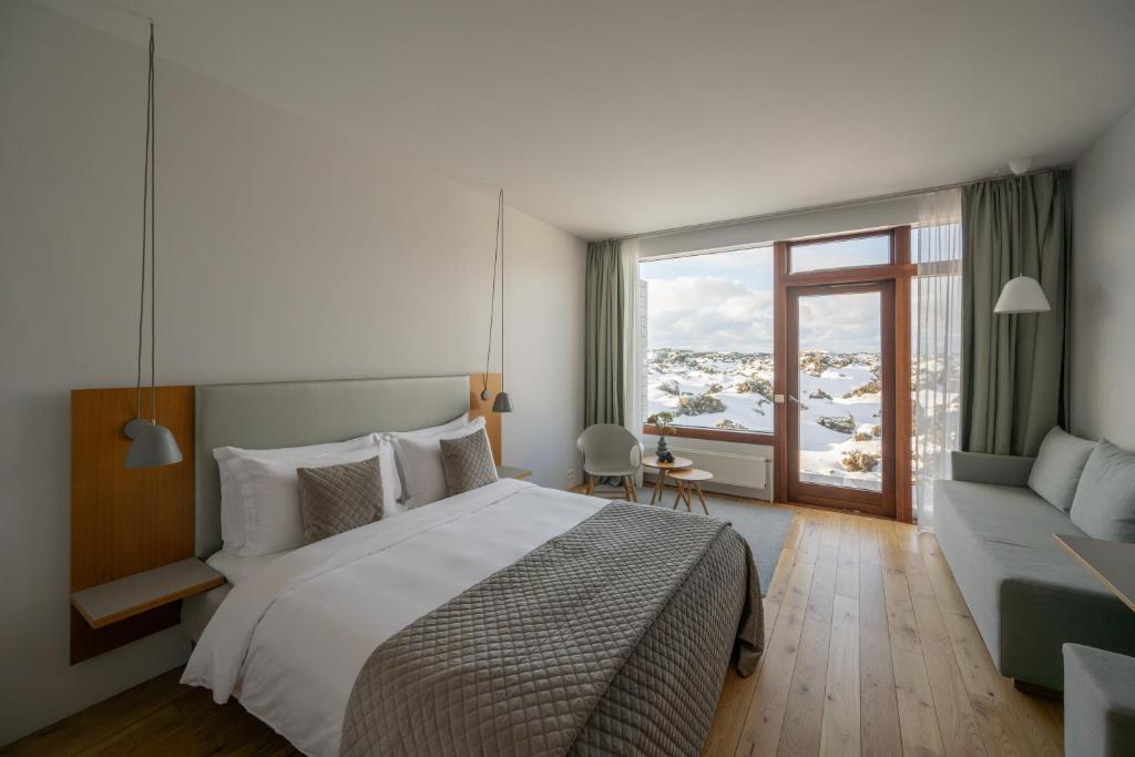 a bedroom with a bed and a couch and a window at Silica Hotel at Blue Lagoon Iceland in Grindavík