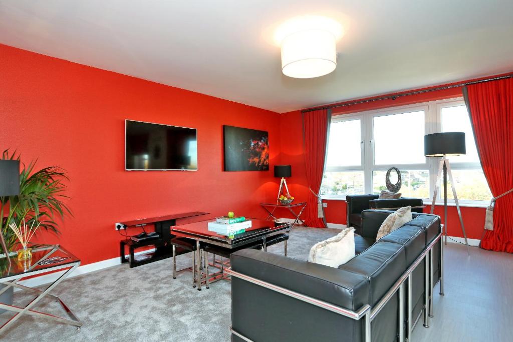 sala de estar con paredes rojas, sofá y mesa en Trendy apartment a short drive from Aberdeen City en Aberdeen