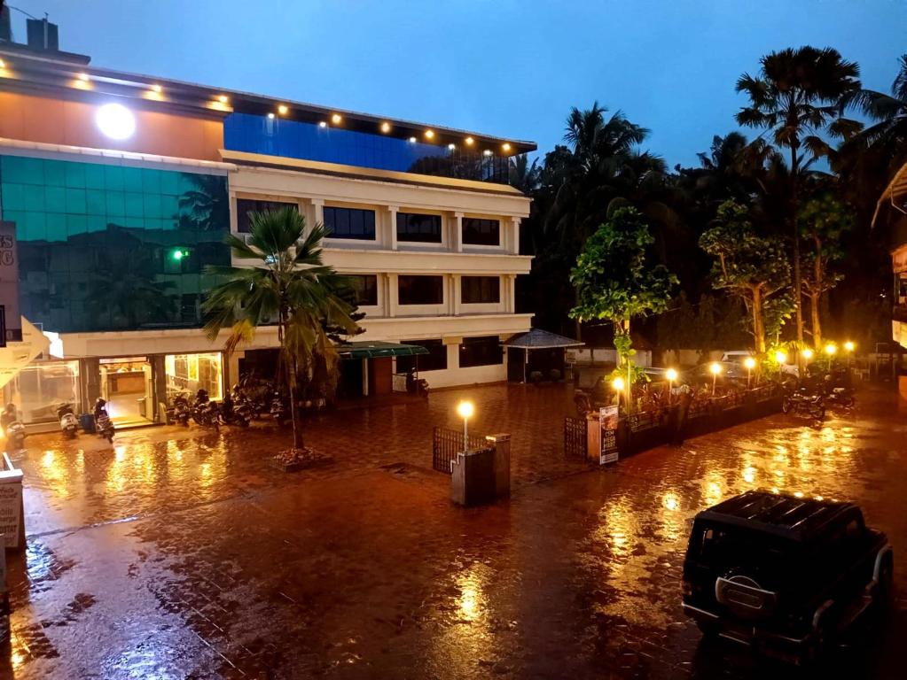 a building with lights on a rainy street at night at Liwa Tower Hotel & Business Center in Kunnamkulam