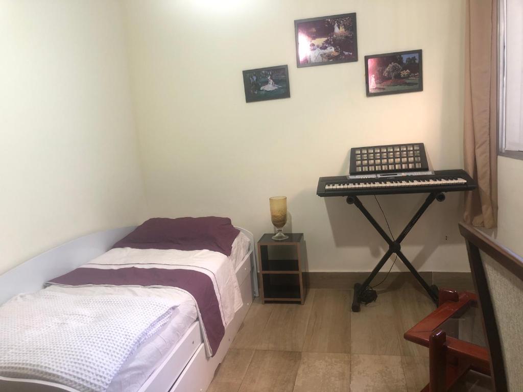 a room with two beds and a keyboard on a table at Quarto privativo Sanilda in Vitória