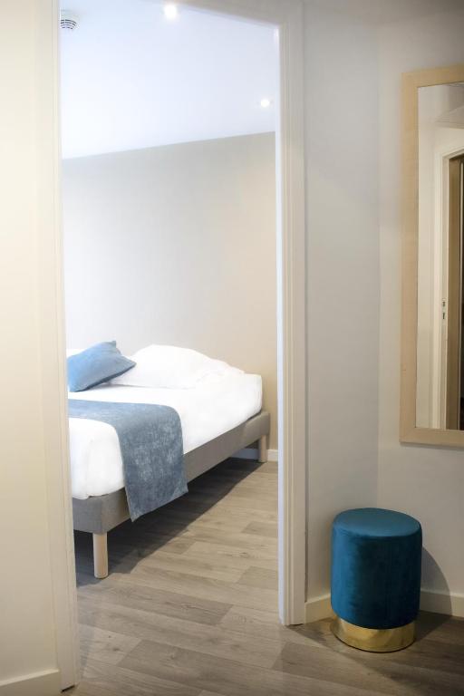 a bedroom with a bed and a blue stool at Tiercé Hotel in Cagnes-sur-Mer