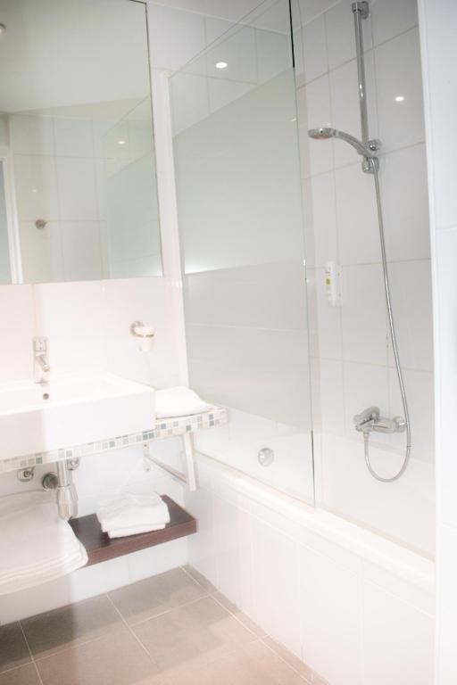 a white bathroom with a shower and a sink at Tiercé Hotel in Cagnes-sur-Mer