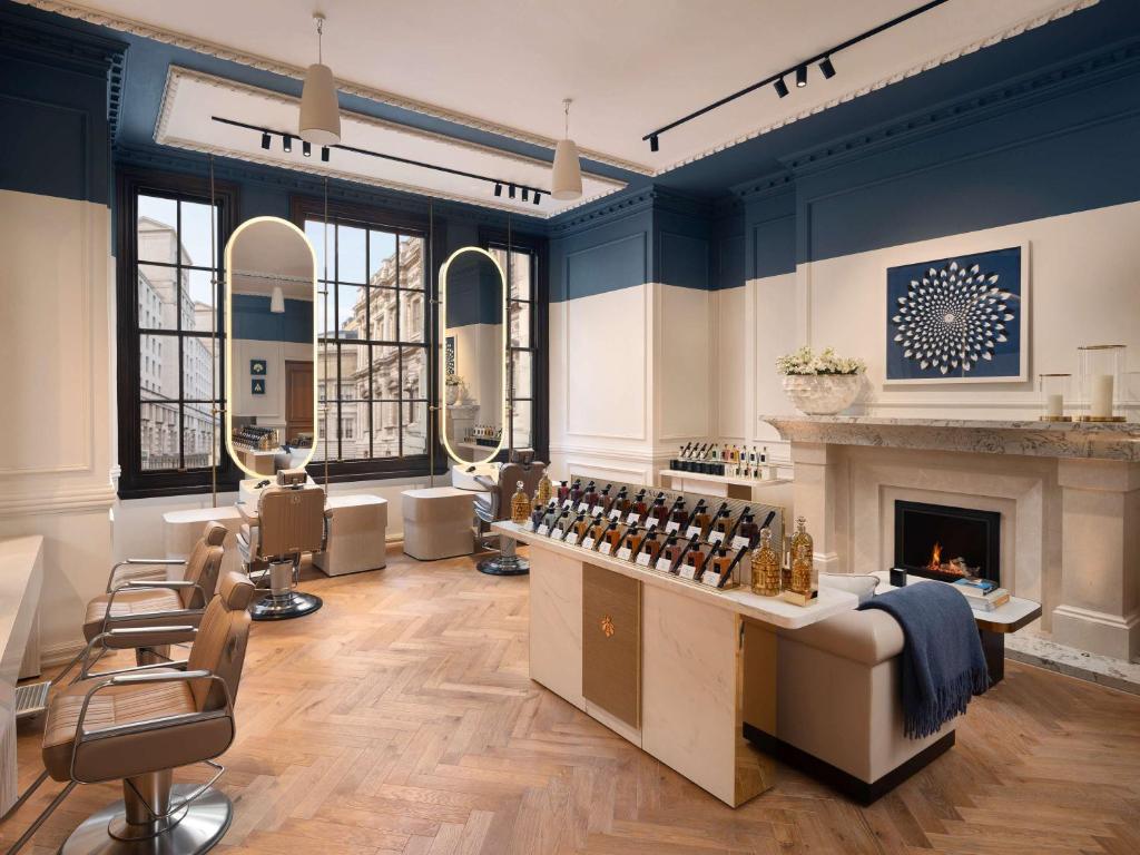 a room with a salon with a fireplace and chairs at Raffles London at The OWO in London