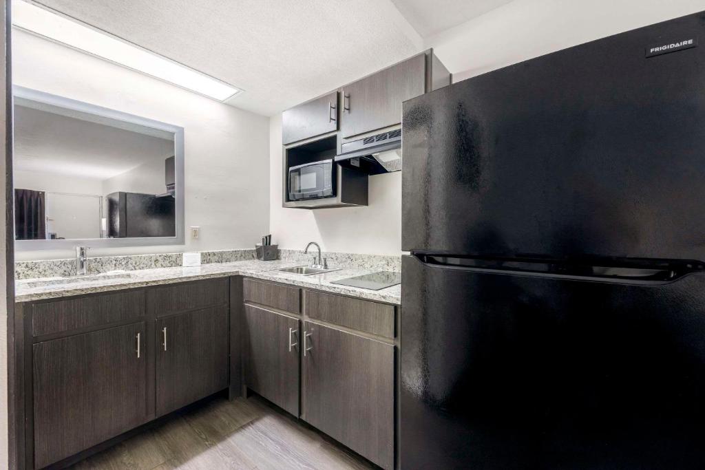 eine Küche mit einem schwarzen Kühlschrank und einer Spüle in der Unterkunft Suburban Studios Cookeville in Cookeville