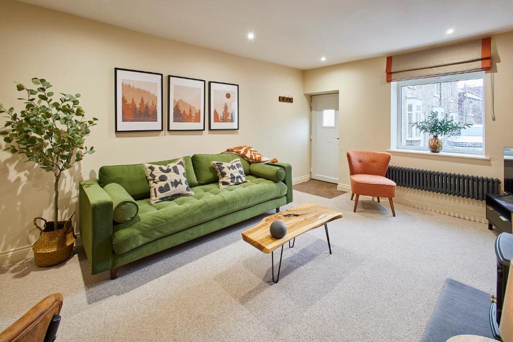 ein Wohnzimmer mit einer grünen Couch und einem Tisch in der Unterkunft Host & Stay - Cinnamon Cottage in Barnard Castle