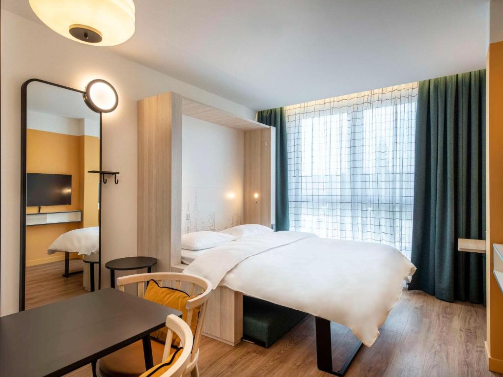 a bedroom with a bed and a table and a mirror at Aparthotel Adagio Access Rouen Centre Cathédrale in Rouen