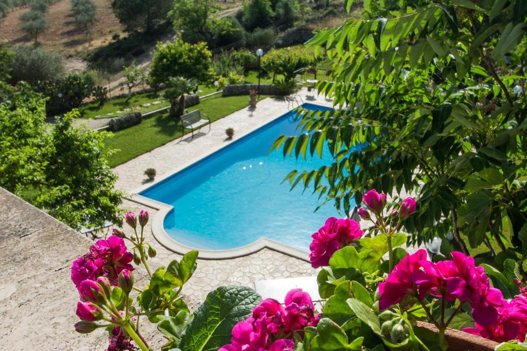 - une piscine dans une cour ornée de fleurs roses dans l'établissement Case Passamonte Agriturismo Resort & Rooms, à Chiaramonte Gulfi