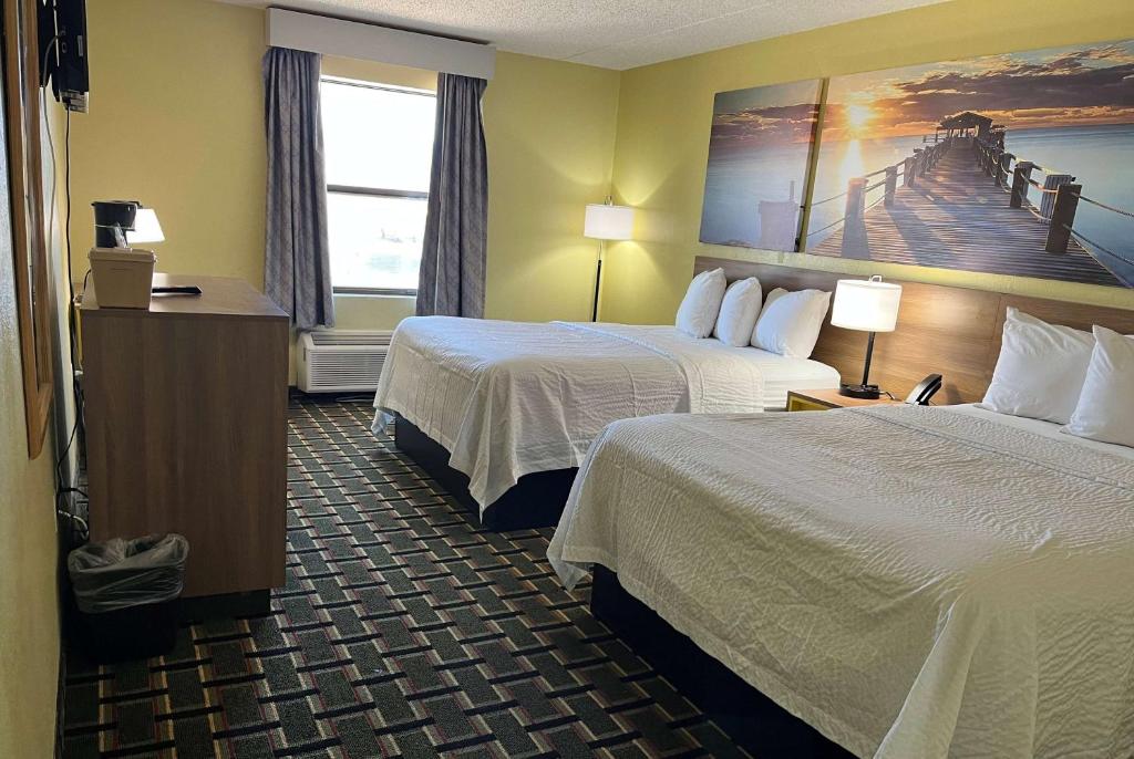 um quarto de hotel com duas camas e uma pintura do cais na parede em Days Inn by Wyndham Park City Kansas em Park City
