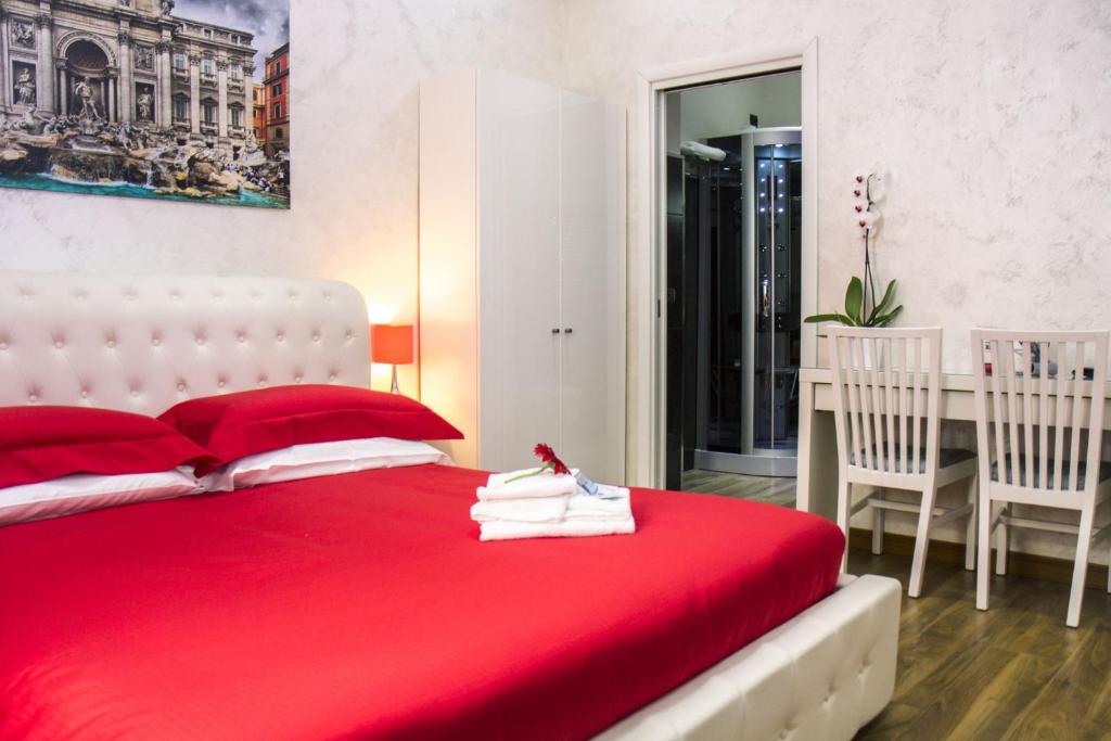 1 dormitorio con 1 cama roja, mesa y sillas en Luxury Rome Savini Guest House, en Roma