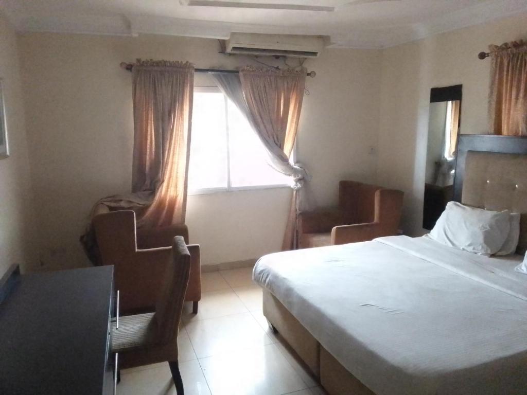 a bedroom with a bed and a desk and a window at St Theresers apartment Lodge 2 in Lekki