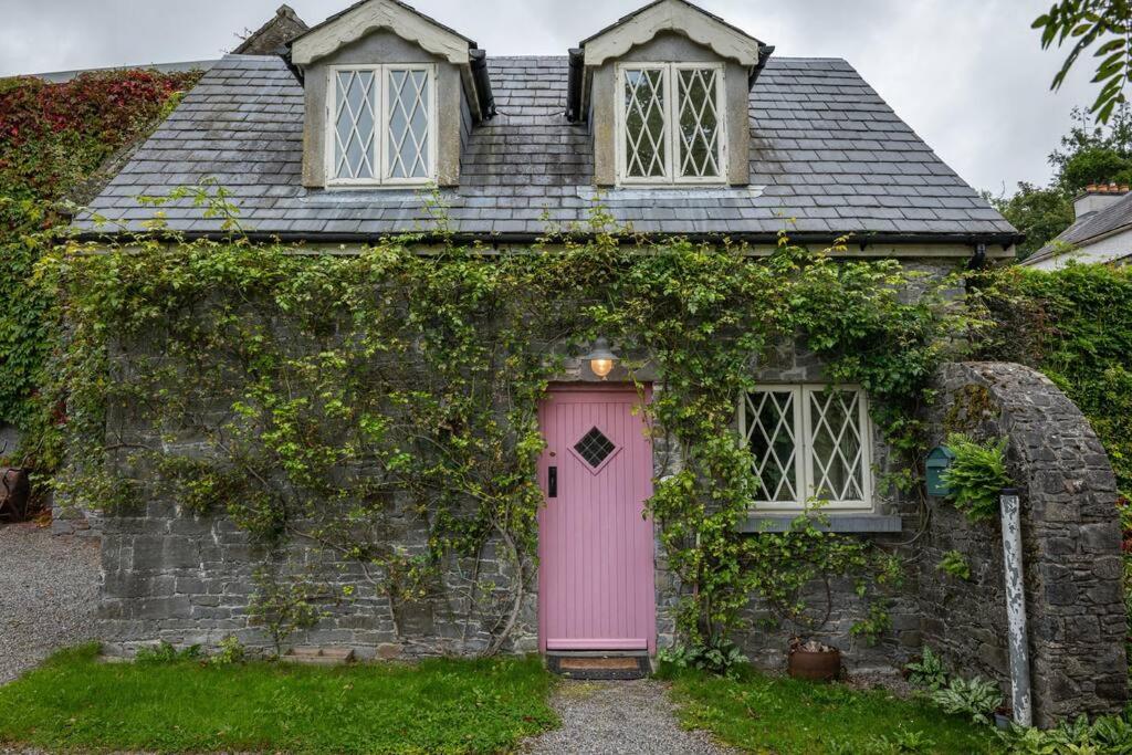 an old house with a pink door and two windows at The Rose Cottage in Thomastown