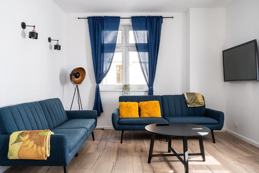 - un salon avec deux canapés bleus et une table dans l'établissement RentPlanet - Apartament Cybulskiego, à Wrocław