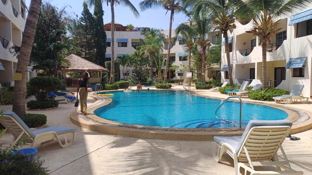 una piscina en un hotel con sillas y palmeras en Amina Haus en Sali Poulang